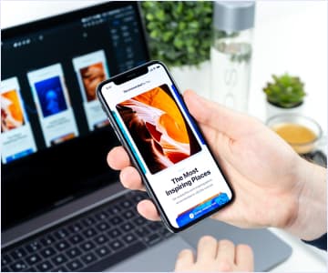 Hand with a cellphone in front of laptop